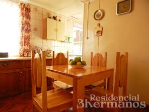 una cocina con una mesa de madera y un bol de fruta. en Residencial Tres Hermanos en Punta Arenas