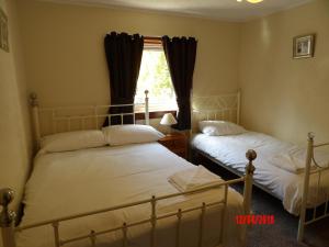 2 Betten in einem Schlafzimmer mit Fenster in der Unterkunft Glen Croft Cottage in Invermoriston