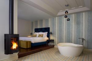 um quarto com uma banheira, uma cama e uma lareira em Convento do Seixo Boutique Hotel & Spa no Fundo