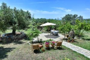 un jardín con mesa, sillas y sombrilla en Nature Villa, en Gerakini