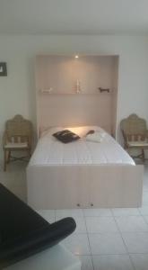 a bedroom with a white bed in a room with two chairs at Les Fontaines Saint Leonard in Honfleur