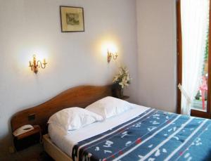 a bedroom with a bed and two lights on the wall at Le Chalet in Luttenbach-près-Munster