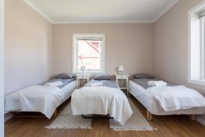three beds in a white room with a window at Grand Villa Stavanger in Stavanger