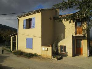 una casa amarilla con puertas azules en una calle en Gîtes des Cèdres en Crestet