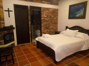 a bedroom with a bed and a cross on the wall at Posadas San Antonio Campestre in Tibasosa