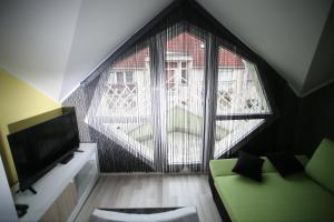 a living room with a green couch and a large window at Centrum Lux 2 Apartmanok in Kaposvár
