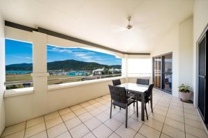 einen Balkon mit einem Tisch und Stühlen sowie Meerblick in der Unterkunft Portside Whitsunday Luxury Holiday Apartments in Airlie Beach