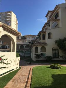 a large building with a brick walkway next to a yard at Playa Muchavista lovely ground floor apartment in El Campello