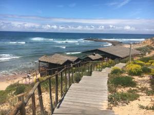 a wooden pathway leading to a beach with the ocean at Pirata hostel Milfontes in Vila Nova de Milfontes