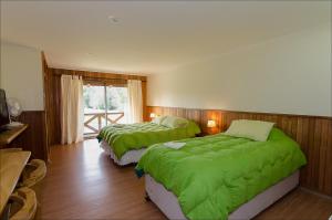 1 dormitorio con 2 camas y mantas verdes en Hotel Boutique Ecoterraverde en Panguipulli