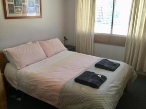 
a bed with a white blanket and pillows at Orford Prosser Holiday Units in Orford
