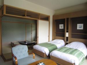 a hotel room with two beds and a chair at Hotel Spax Kusatsu in Kusatsu