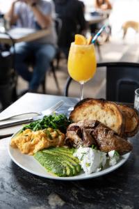 a plate of food with meat and bread and a glass of orange juice at Kirketon Hotel Sydney in Sydney