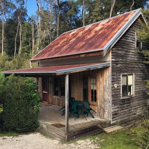 una pequeña casa de madera con techo rojo en Corinna Wilderness Village, en Corinna