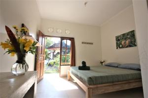 a bedroom with a bed and a vase of flowers at Villa Ricca Eco Lodge in Uluwatu