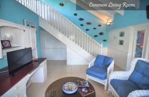 a living room with a staircase with a tv and blue walls at Moon San Villa at the Blue Lagoon in Port Antonio