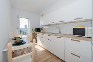 グダニスクにあるFeel Summer Vibes At 3BR Panoramic View Apartmentのキッチン(白いキャビネット、テーブル、電子レンジ付)