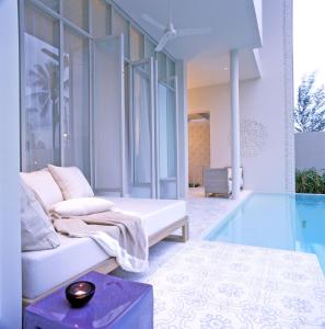 a living room with a couch and a glass pool at SALA Phuket Mai Khao Beach Resort - SHA Plus in Mai Khao Beach