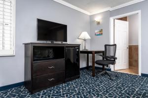 um quarto de hotel com uma televisão e uma secretária com uma cadeira em Dusk Hotel Hollywood em Los Angeles