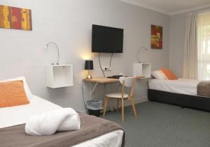 a bedroom with two beds and a desk with a television at Ballina Byron Islander Resort and Conference Centre in Ballina