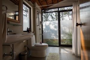 a bathroom with a toilet and a sink and a window at Dhole's Den Bandipur in Bandipūr +28 photos