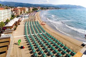 
a beach filled with lots of beach chairs and umbrellas at Hotel Villa Igea in Diano Marina
