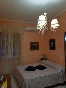 een slaapkamer met een bed en een kroonluchter bij Bed and breakfast Marilena in Montegiordano
