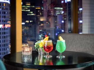 two cocktails on a table with a view of the city at Ibis Ambassador Myeongdong in Seoul
