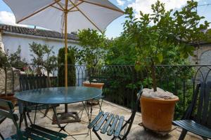 une terrasse avec une table, des chaises et un parasol dans l'établissement Bel Appartement Dans Cloitre Arbore, à Villeneuve-lès-Avignon