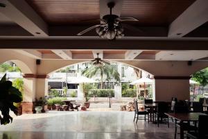 un ristorante con ventilatore a soffitto, tavoli e sedie di Mike Beach Resort a Centro di Pattaya