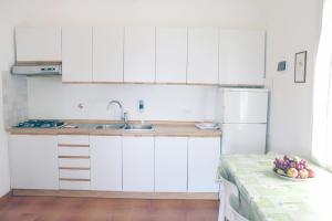 een keuken met witte kasten en een tafel met een fruitschaal bij Villa Cedro in Capoliveri