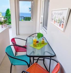a glass table with chairs and drinks on a balcony at Sea Breeze Flat in Kavála