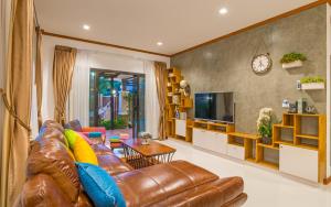 ein Wohnzimmer mit einem Ledersofa und einem TV in der Unterkunft Villa De Sea Aonang in Ao Nang Beach