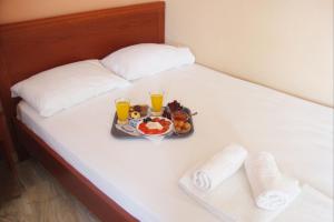 a tray of food on a bed with two glasses of orange juice at Hotel Pantazis in Paralia Panteleimonos