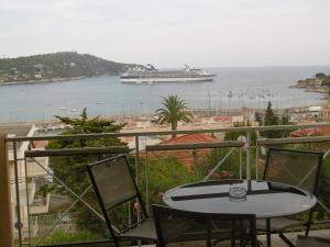 a balcony with a table and a cruise ship in the water at Hôtel La Flore in Villefranche-sur-Mer