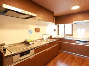 a kitchen with wooden cabinets and a sink and a counter at K's House Takayama Oasis [2nd K's Hostel] in Takayama