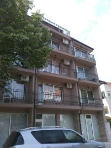 a building with balconies and a car parked in front of it at Guest House Stenli in Primorsko