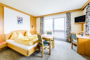 a bedroom with a bed and a desk and a table at Landhotel Kolb in Haus im Ennstal