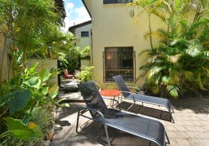 a patio with chairs and a table and a building at Sea La Villa Port Douglas in Port Douglas