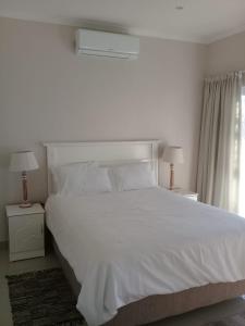 1 dormitorio con 1 cama blanca grande y 2 lámparas en Broadway Bay Accommodation, en Durban