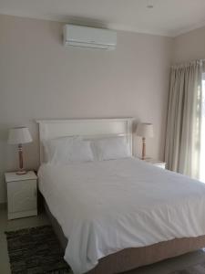 a bedroom with a large white bed with two lamps at Broadway Bay Accommodation in Durban