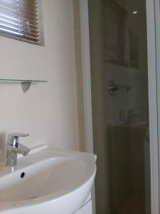 uma casa de banho branca com um lavatório e um chuveiro em Broadway Bay Accommodation em Durban
