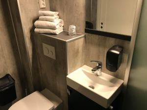 a bathroom with a sink and a toilet and towels at Rørosvidda Hotell in Røros