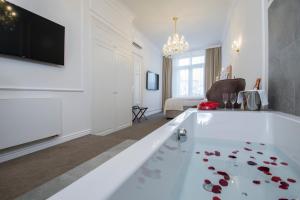 Apartmány Arte في برنو: غرفة معيشة مع حوض استحمام أبيض كبير مع ورود حمراء على الأرض