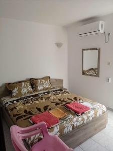 a bedroom with a bed with two pillows and a pink chair at Guestrooms Stoyanovi in Chernomorets