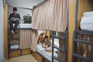 a woman is sitting in a bed in a bunk room at Peace Factory Hostel in Bangkok