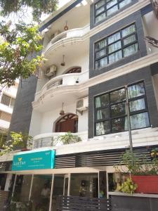 - un grand bâtiment blanc avec un panneau vert devant dans l'établissement Luxtay Suites, à Bangalore