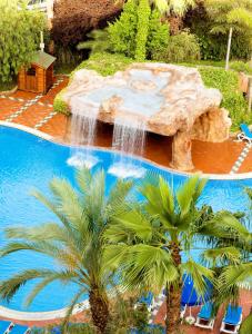 a swimming pool with a waterfall and palm trees at H10 Salauris Palace in Salou