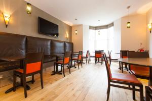 a restaurant with a leather couch and tables and chairs at The Abbey Lodge Hotel in Bradford