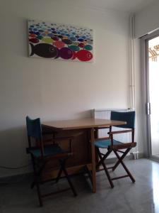 a wooden table with two chairs and a painting on the wall at Les Caroubiers in Roquebrune-Cap-Martin